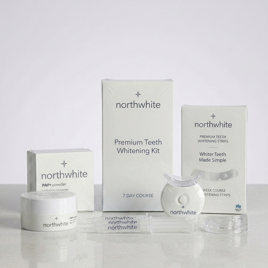 Northwhite Premium Teeth Whitening Kit displayed with its white packaging boxes, a small jar of powder, and a clear handheld device on a light gray reflective surface.